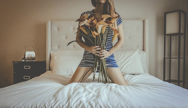 Žena s kyticou kvetou sediaca na posteli